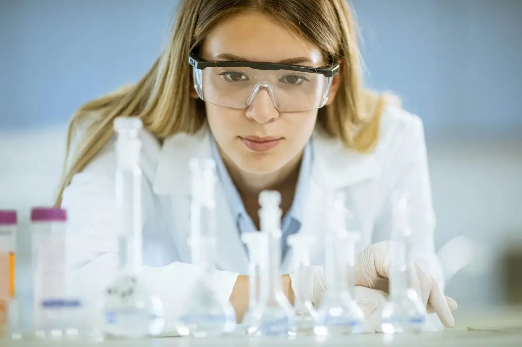 Female medical or scientific researcher looking at a flasks with solutions in a laboratory